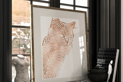 Framed artwork of a cat on a shelf with books and a sculpture.