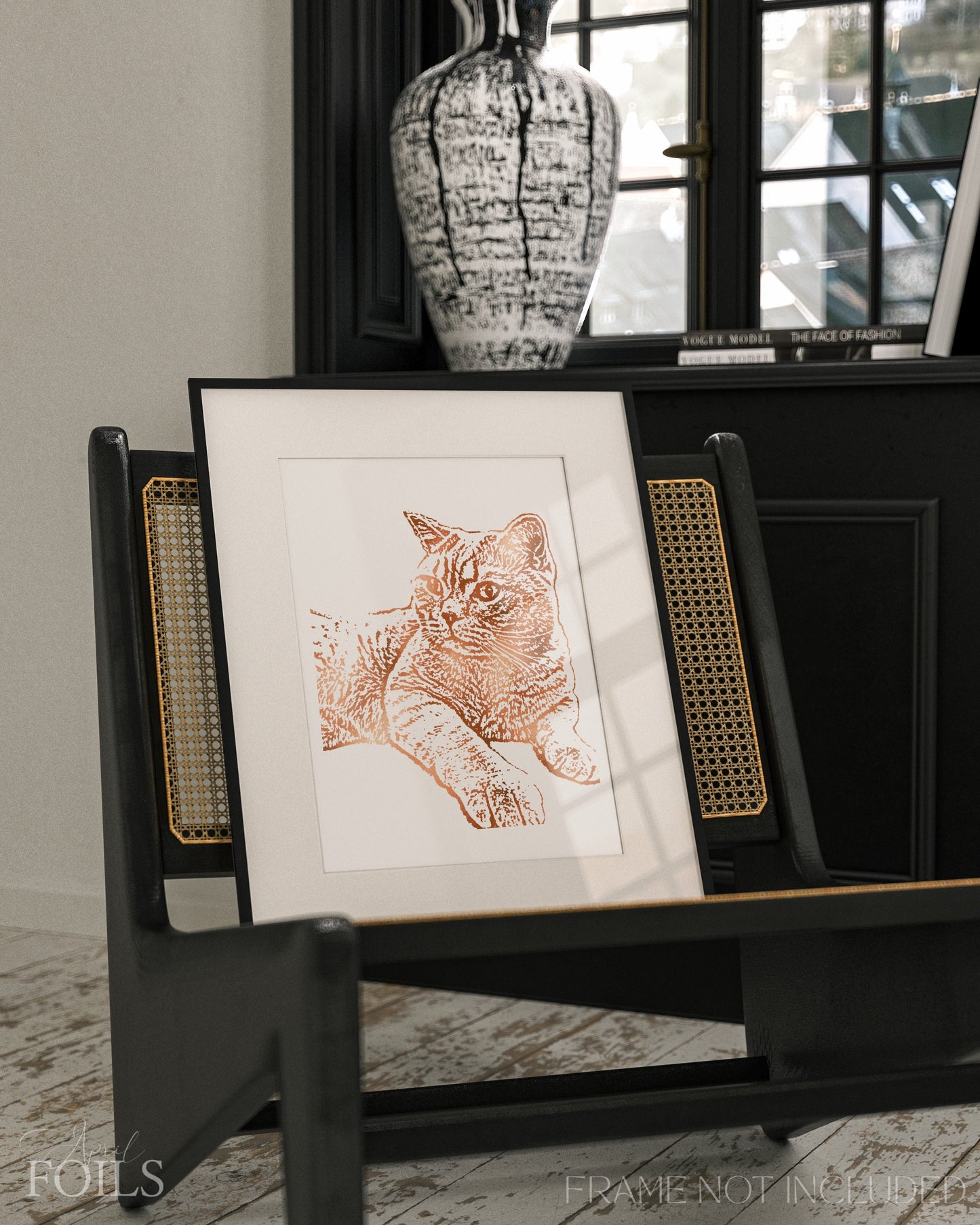 Framed foil artwork of a pet cat on a black stand with a vase in the background.