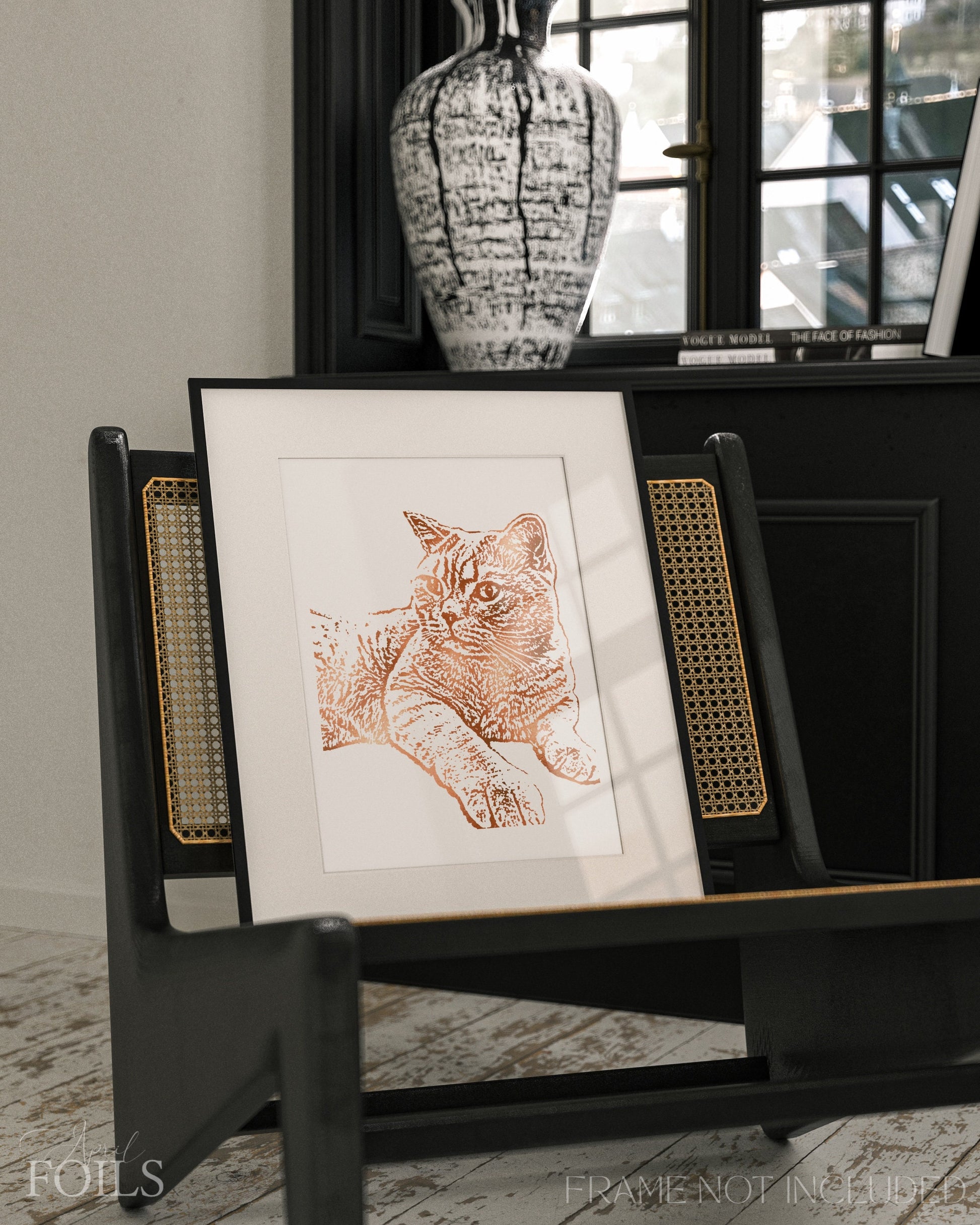 Framed foil artwork of a pet cat on a black stand with a vase in the background.